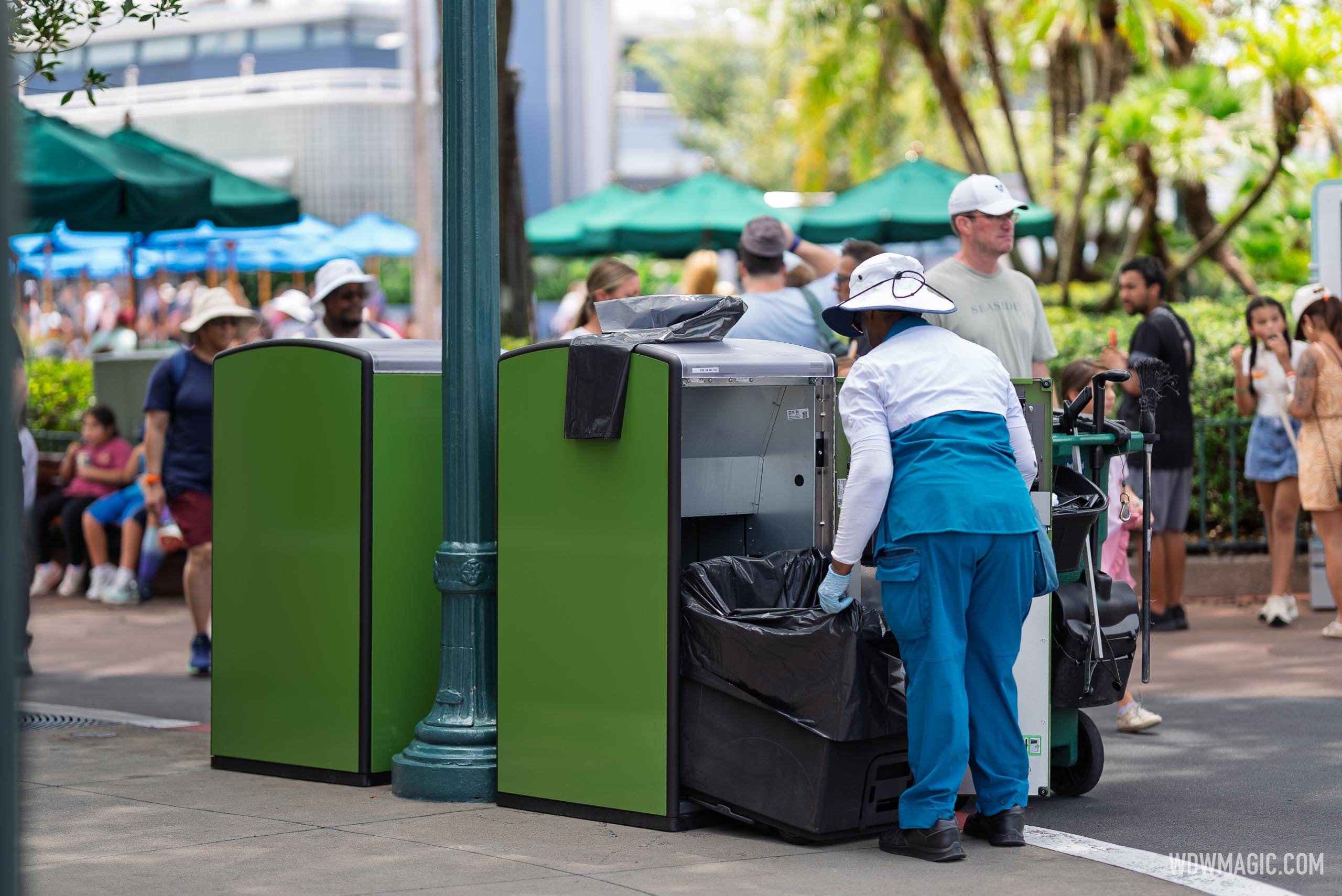 A custodial cast member empties a new green solar-powered trash bin at Disney's Hollywood Studios