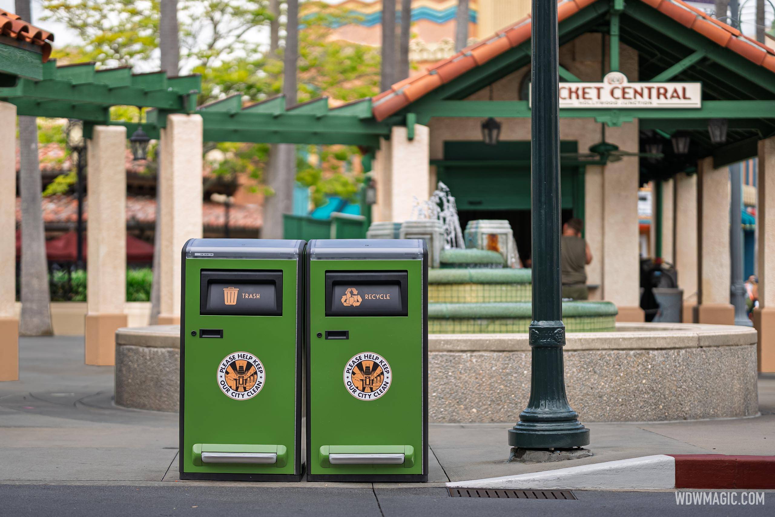 New green solar-powered trash and recycling bins sit near the Ticket Central fountain plaza at Disney's Hollywood Studios, complete with a "Please Help Keep Our City Clean" decal