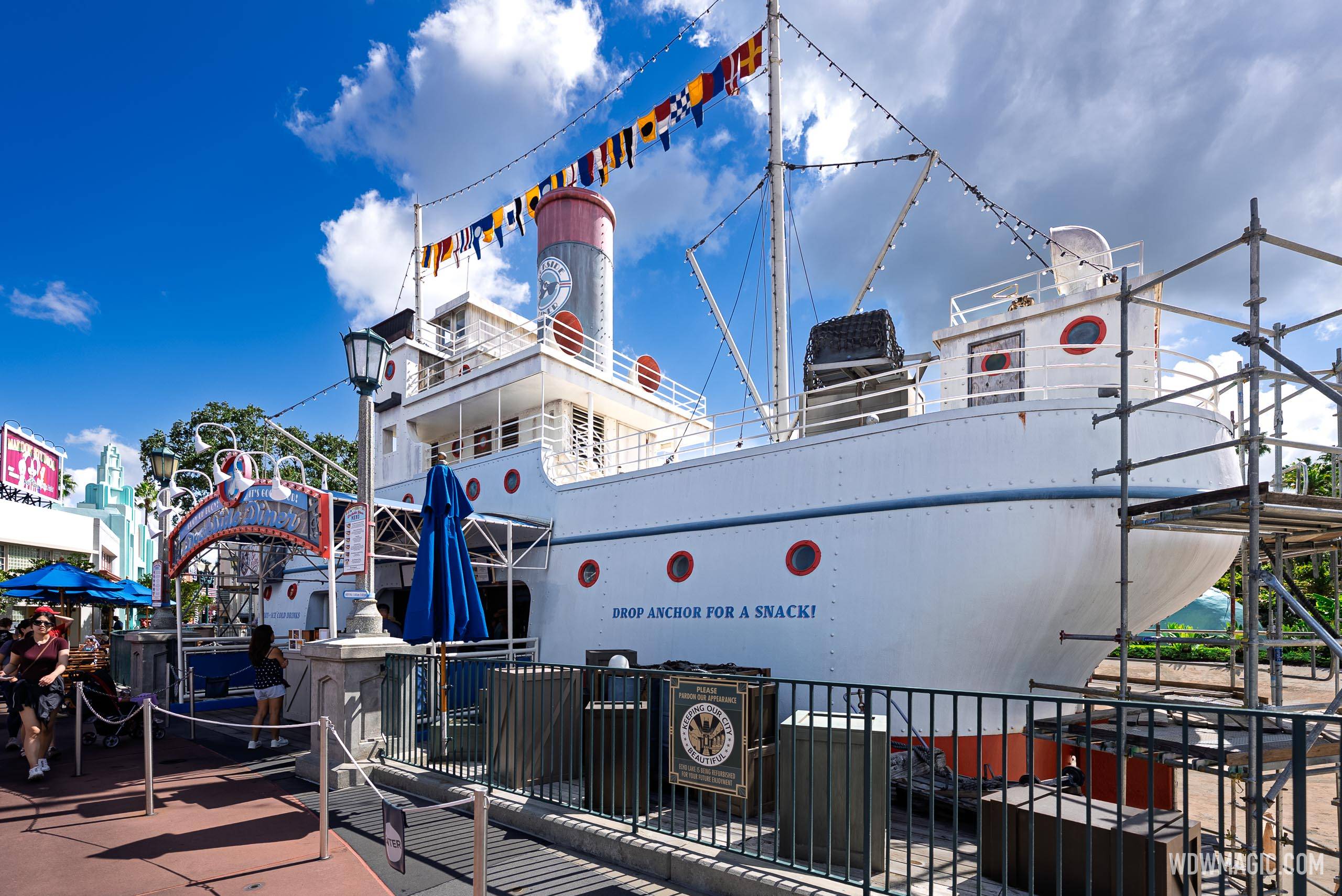 Scaffolding covers the starboard side of the S.S. Down the Hatch vessel, with the "Drop Anchor for a Snack" signage still visible on the hull