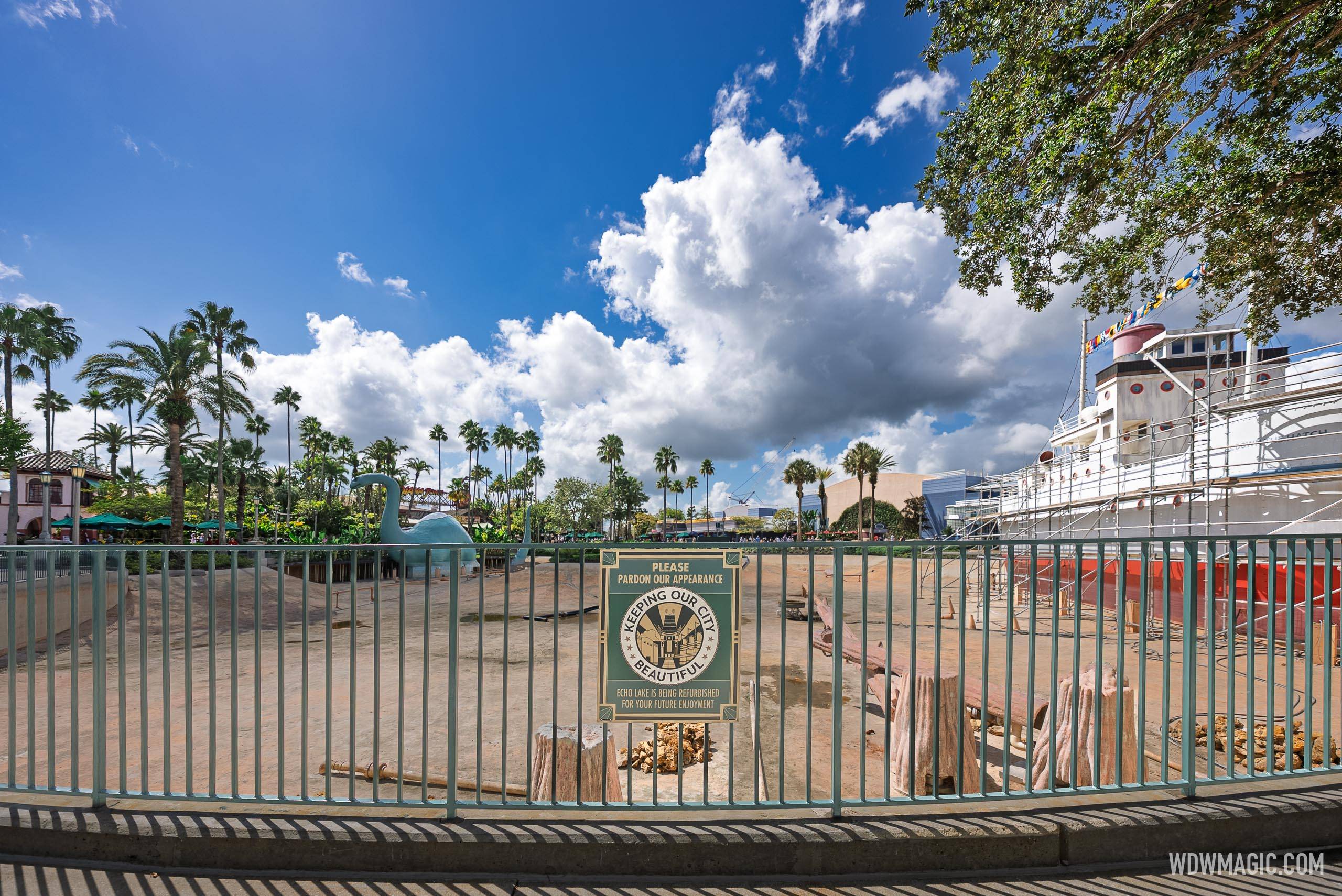 A "Keeping Our City Beautiful" construction sign on the perimeter fence notes that Echo Lake is being refurbished, with the drained basin and scaffolded S.S. Down the Hatch visible behind it