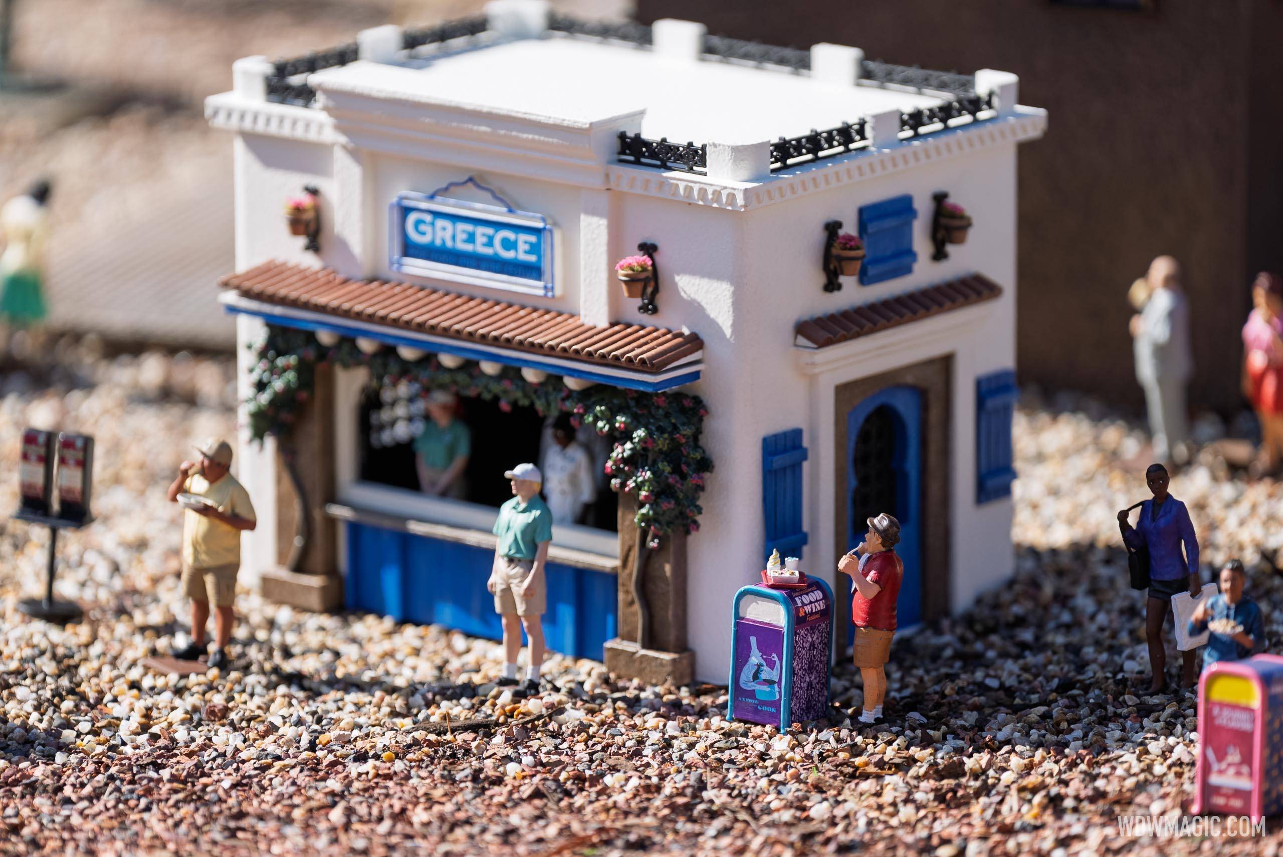 The Greece booth miniature, complete with tiny figures and blue-accented Mediterranean architecture, in the Germany pavilion's train garden Food & Wine Festival display
