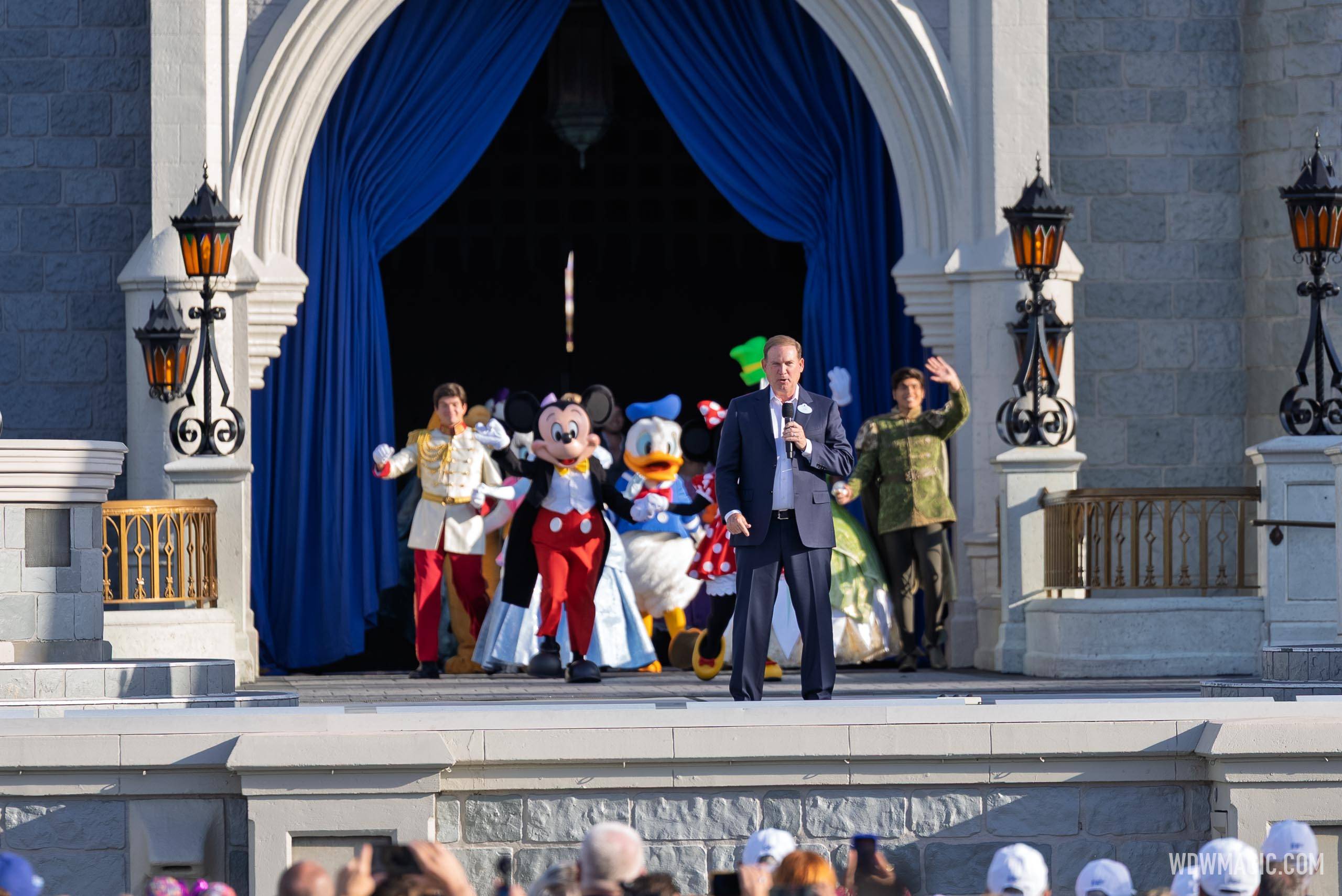 Joe Schott speaks to guests from the Cinderella Castle stage with Mickey, Minnie, Donald, Daisy, and Disney princes and princesses during the Walt Disney World 55th anniversary celebration