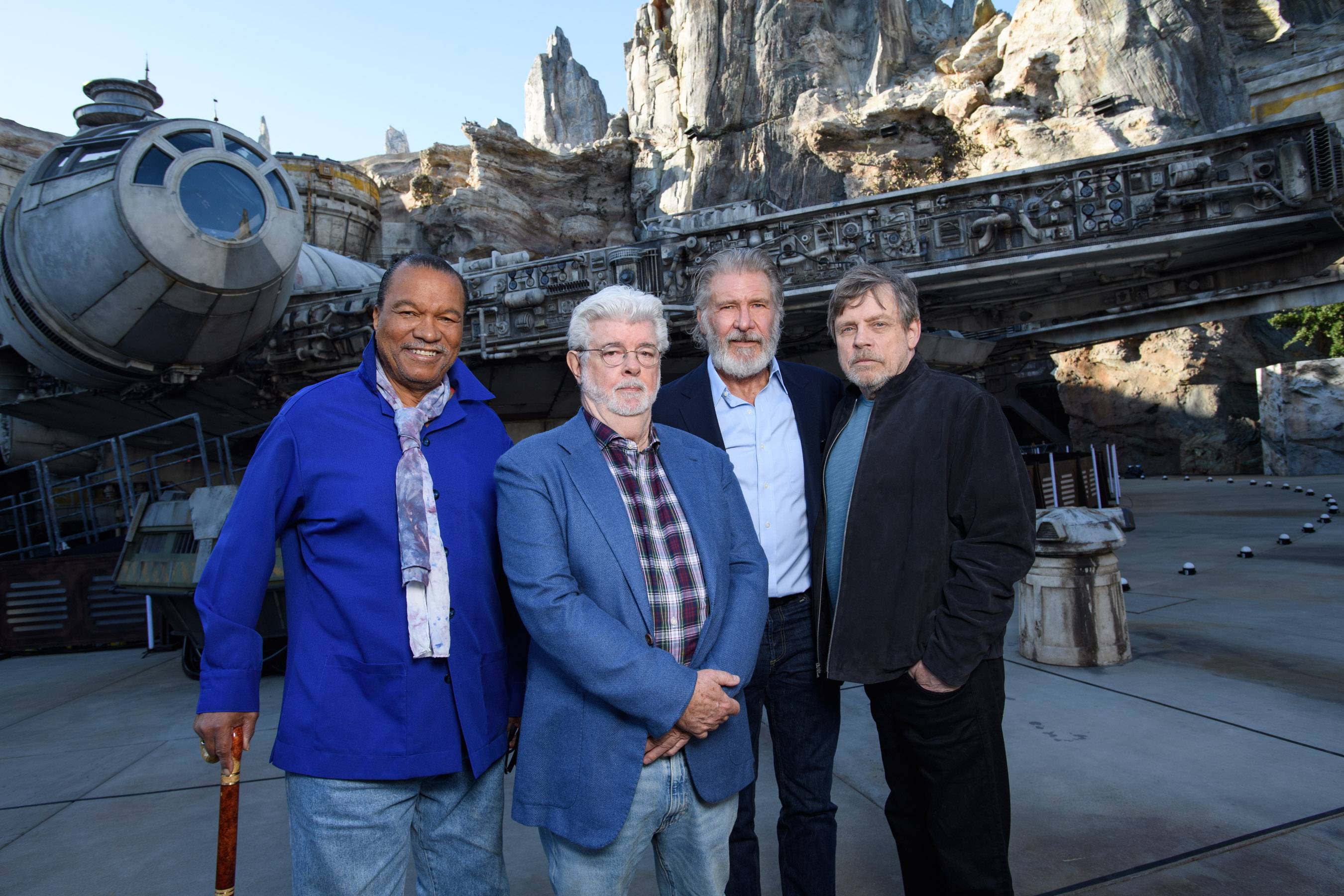 Actor Billy Dee Williams, Star Wars creator George Lucas, actors Harrison Ford and Mark Hamill pose in front of the Millennium Falcon at Star Wars: Galaxy’s Edge at Disneyland