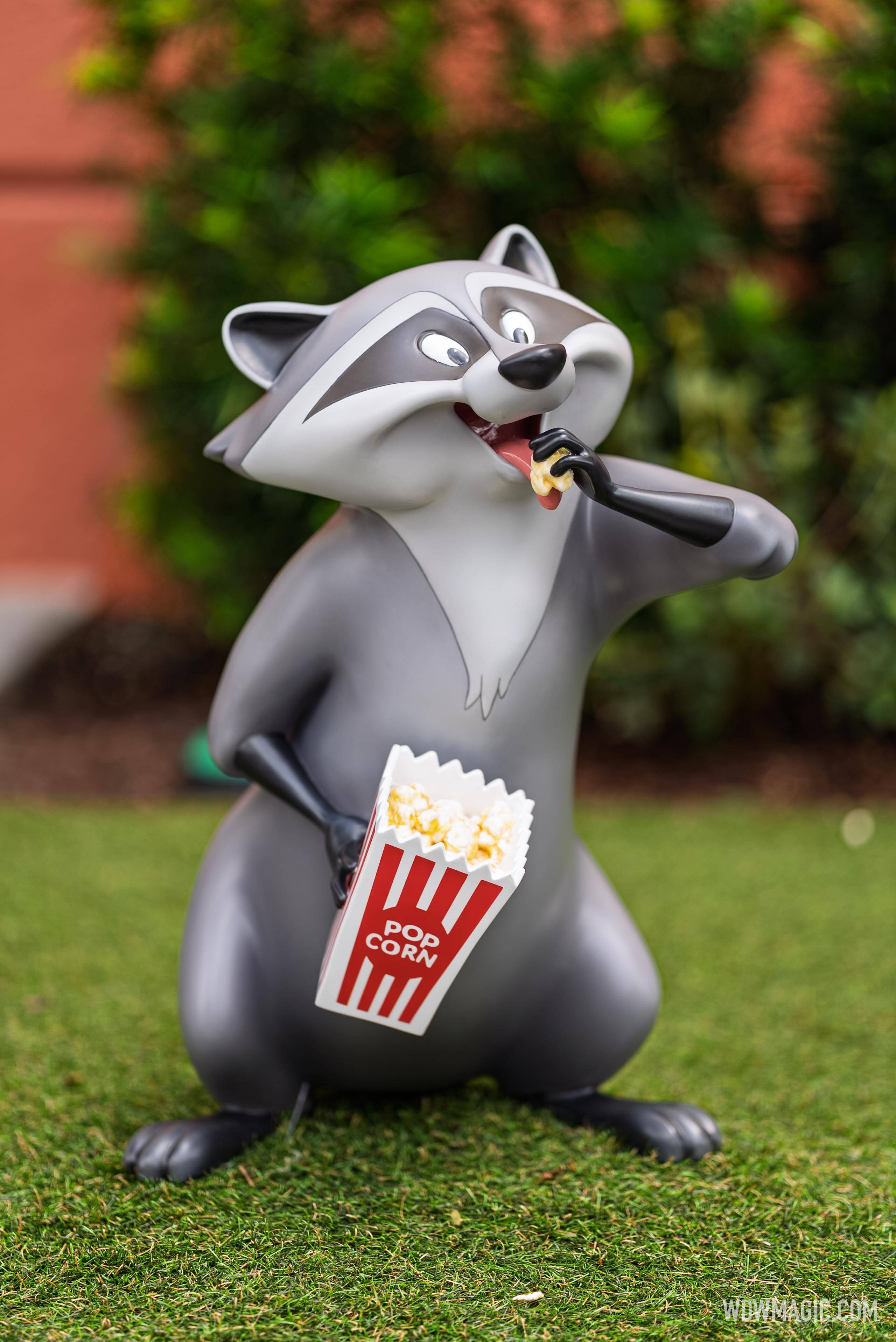Meeko from Pocahontas holds a popcorn bucket and snacks in the Walt Disney Studios courtyard outside The Magic of Disney Animation