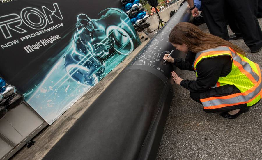 PHOTO - Magic Kingdom cast members sign one of the first steel support columns for the upcoming TRON coaster