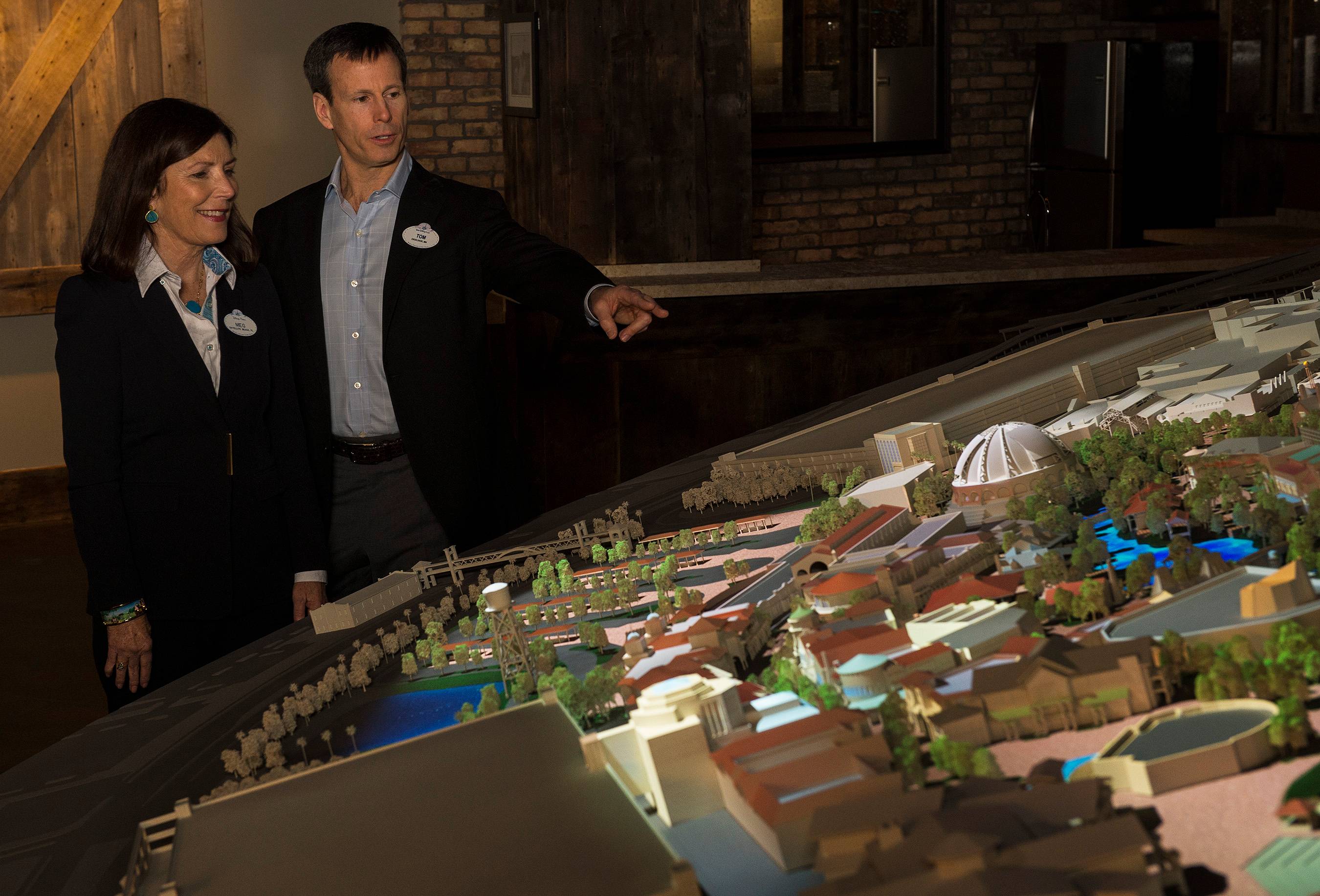 Meg Crofton, and Tom Staggs look over the model of the Disney Springs expansion
