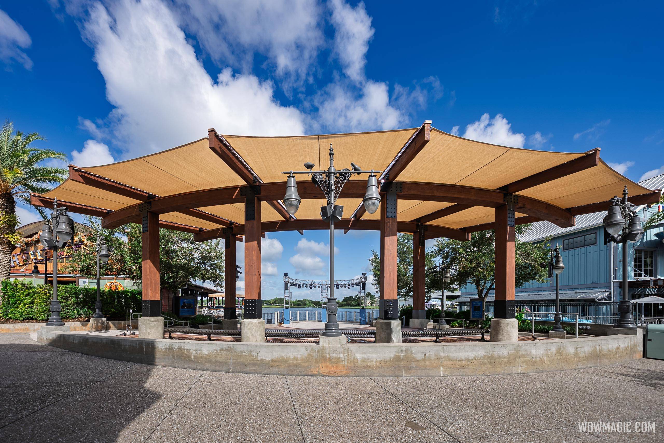 The new Waterview Park shade canopy with its tan sail panels and dark wood frame, looking through toward Village Lake