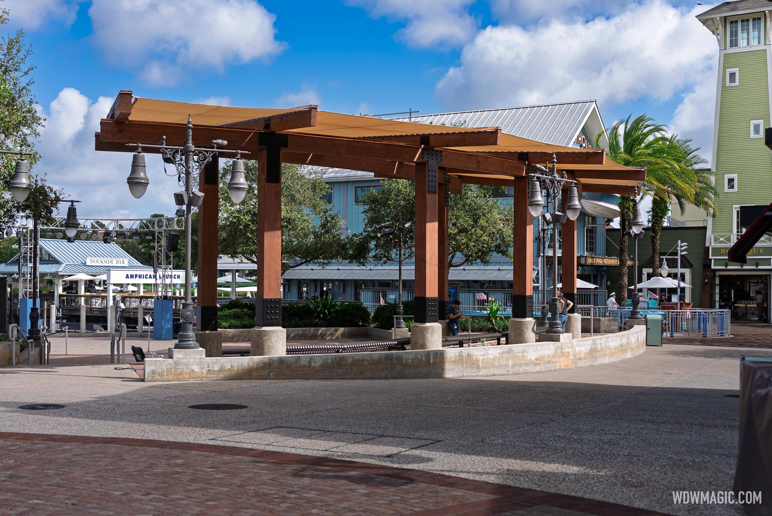 The new Waterview Park shade canopy with its warm tan sail panels and dark wood frame, with the Amphicar Launch and Dockside Bar signs visible to the left