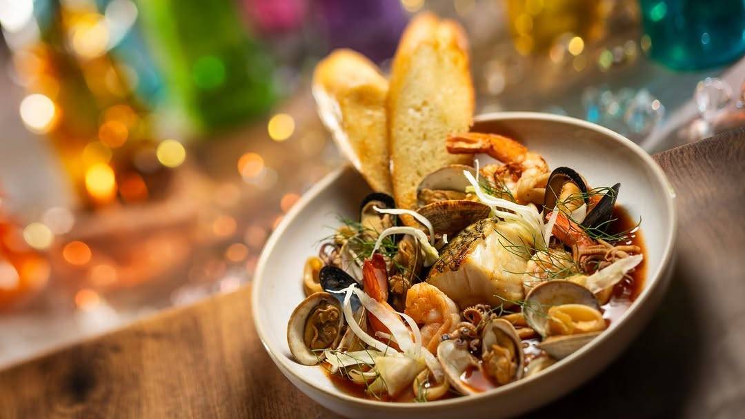 Cioppino: Black bass, clams, shrimp, calamari, mussels, crispy garlic chips, and sourdough croutons