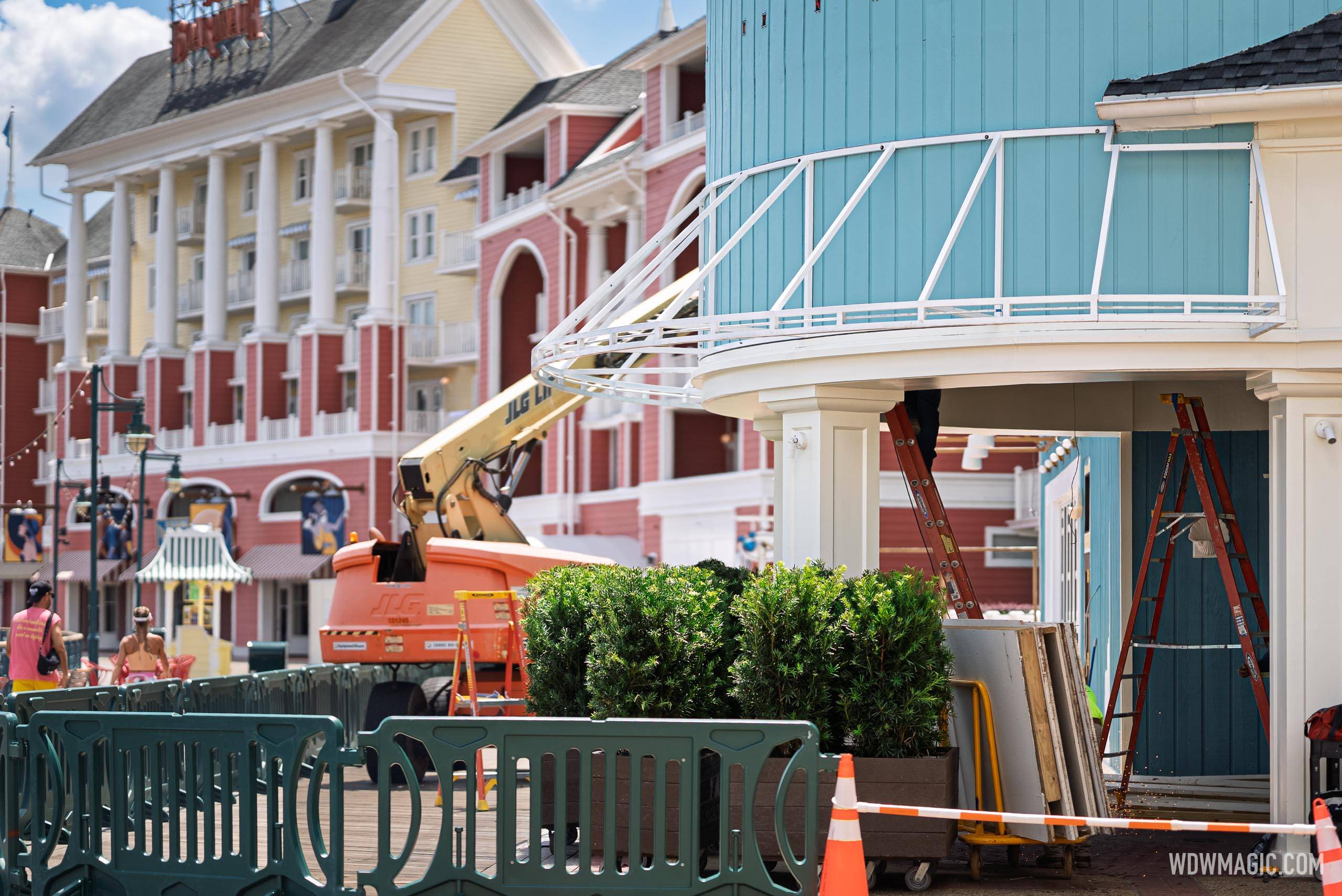 Ladders and construction materials are staged beneath the curved marquee frame on the teal Hurly-Burly building