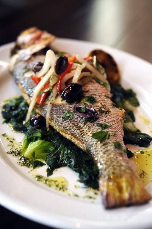 TRADITIONAL WHOLE FISH: At Kouzzina by Cat Cora at Disney’s BoardWalk Resort, whole fish is pan roasted and served with braised greens, Greek olives, fennel and smoked chili. Copyright 2009 The Walt Disney Co.