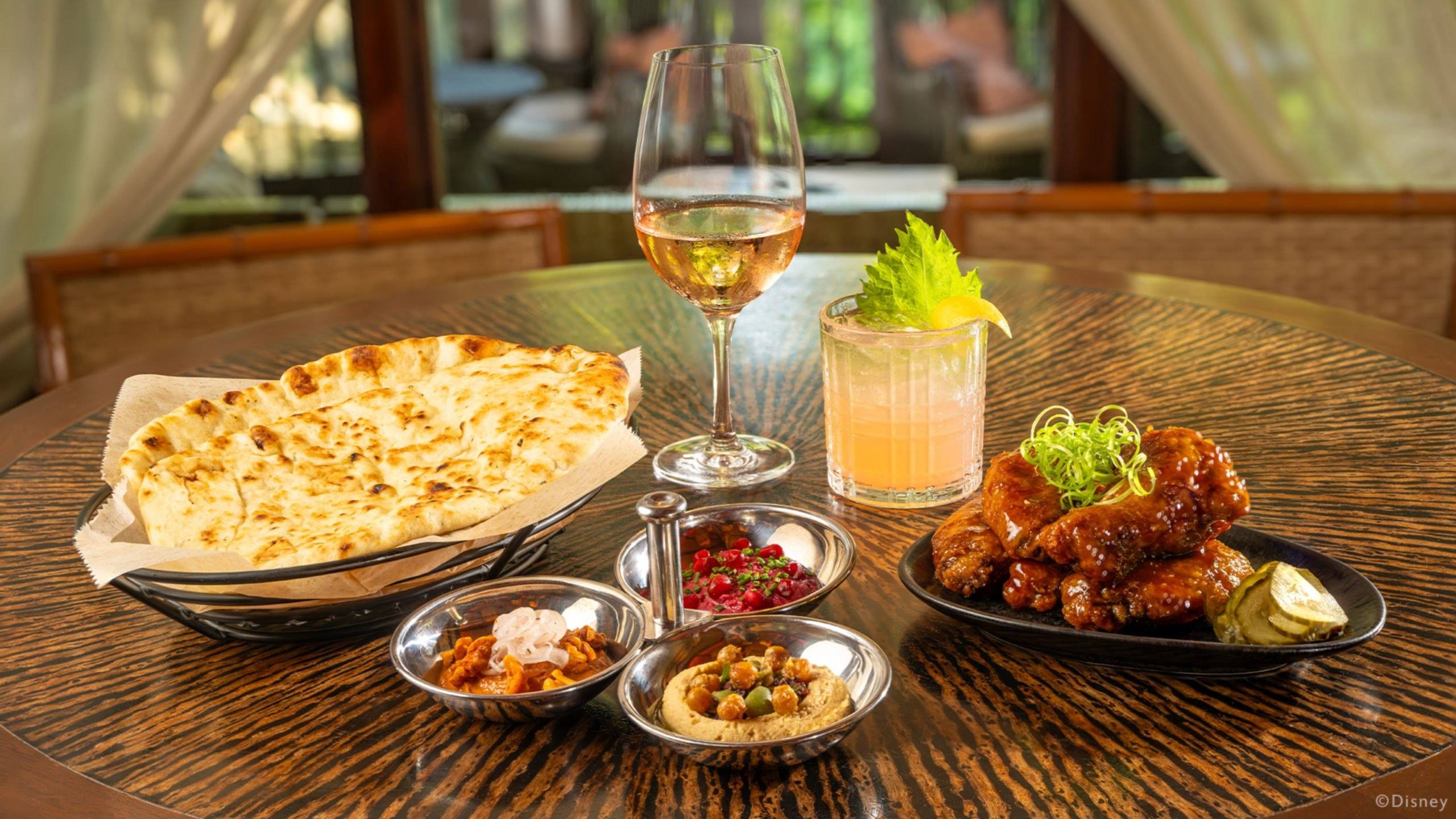 Nomad Lounge naan, dips and glazed chicken wings beside two specialty beverages