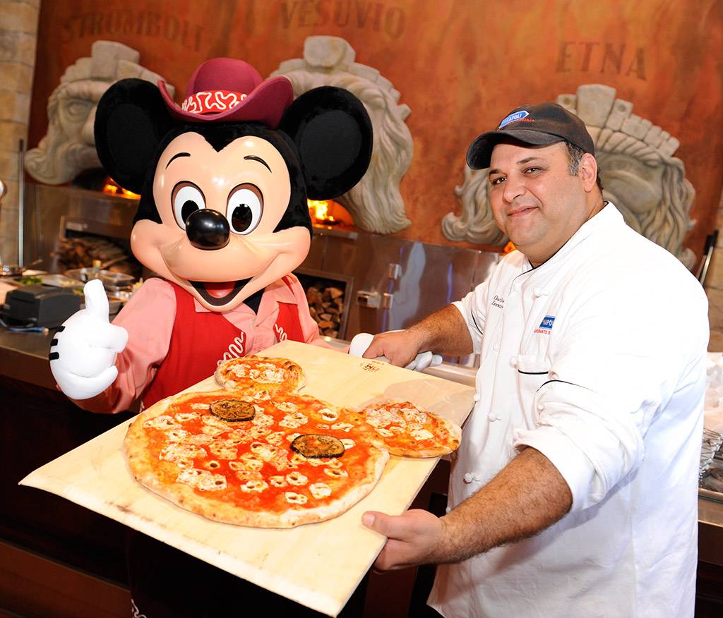 VIA NAPOLI: Executive Chef Charlie Restivo poses with Mickey Mouse and a special Mickey-shaped pizza Aug. 5, 2010 during the grand opening of the authentic Neapolitan pizzeria in the Italy pavilion at Epcot World Showcase. Via Napoli, operated by Patina Restaurant Group, features wood-burning ovens – and will use water from a source that most resembles the water in Naples, Italy, home of some of the world’s best pizza dough. The 300-seat pizzeria features a menu inspired by the famous pizzerias of southern Italy. The menu also features pastas, salads, sandwiches and Italian wines. (Gene Duncan, photographer) 