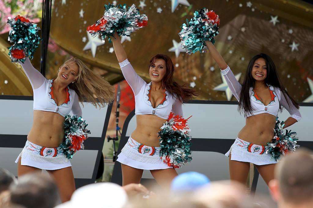 Clad in their famous white bikini tops and mini skirts, the Miami Dolphins  cheerleaders pose with their pom poms prior to their performance during the  2011 KISS Country 99.9 FM Chili Cookoff