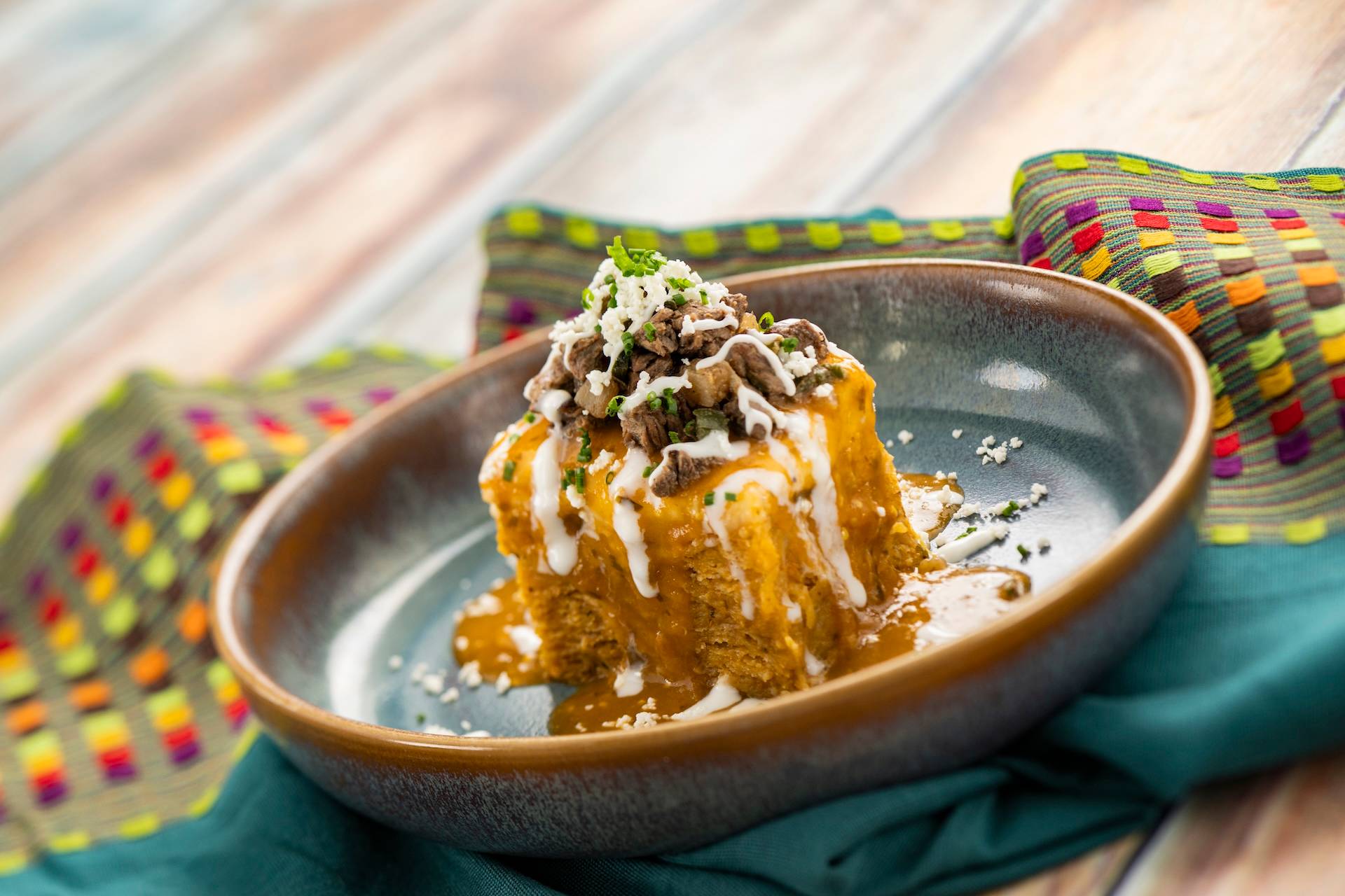 Chilaquiles con Carne: Corn tortillas tossed in salsa ranchera and monterey jack with shaved rib-eye, poblano peppers, onions, queso fresco, and crema mexicana (New)