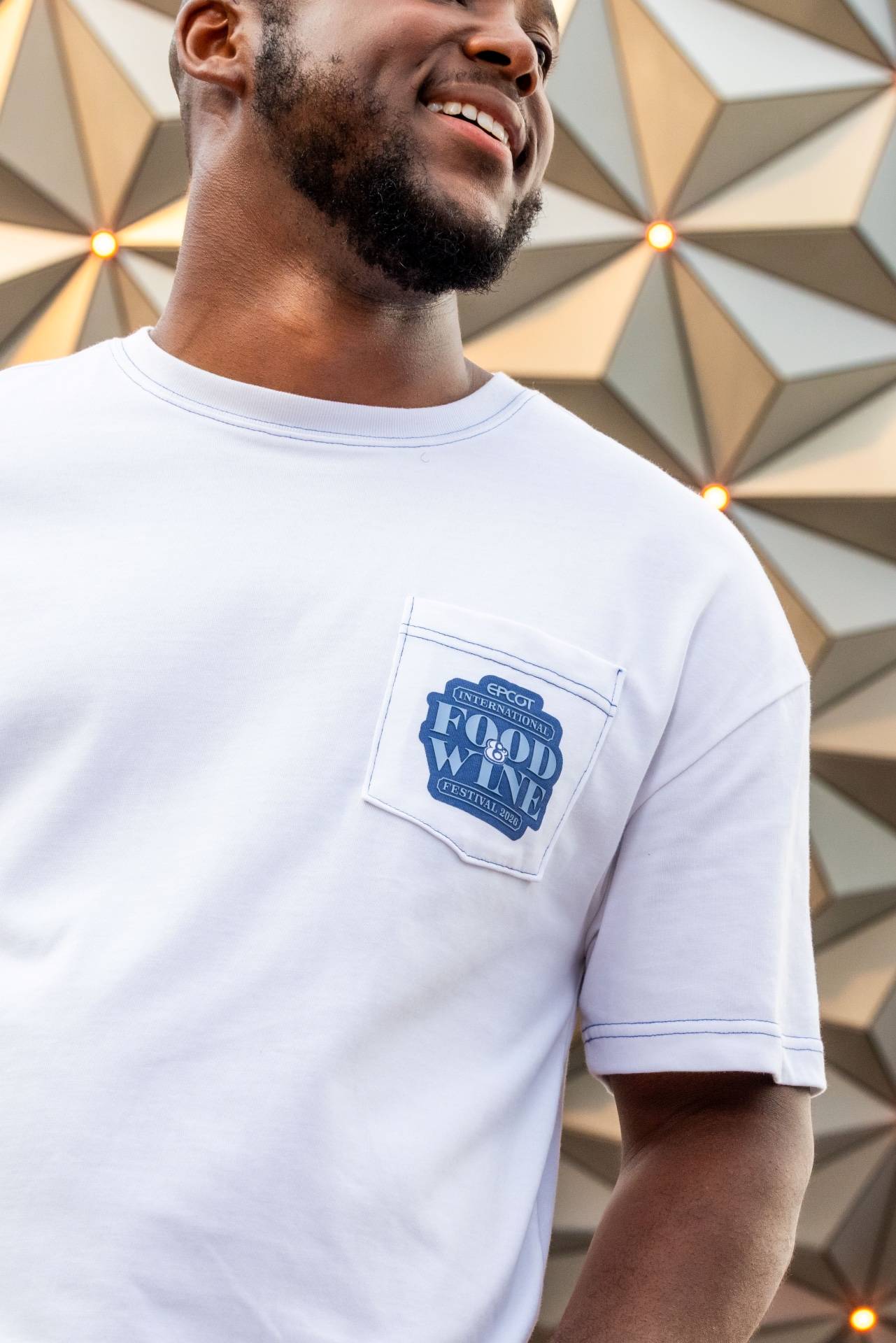 White EPCOT International Food & Wine Festival 2026 pocket tee modeled in front of Spaceship Earth