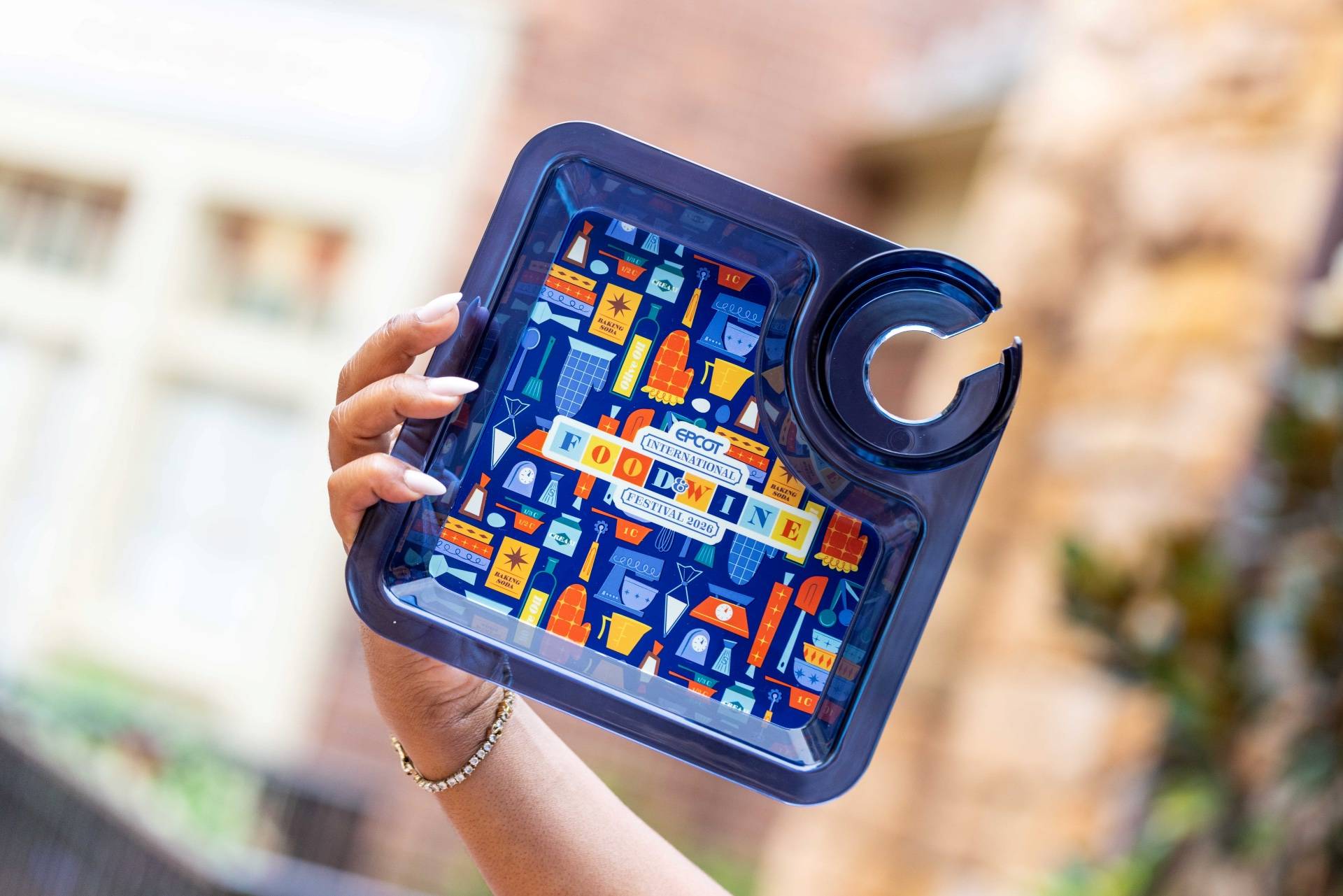 EPCOT International Food & Wine Festival 2026 snack tray with built-in cup holder, featuring the festival's bold kitchen-themed graphic pattern