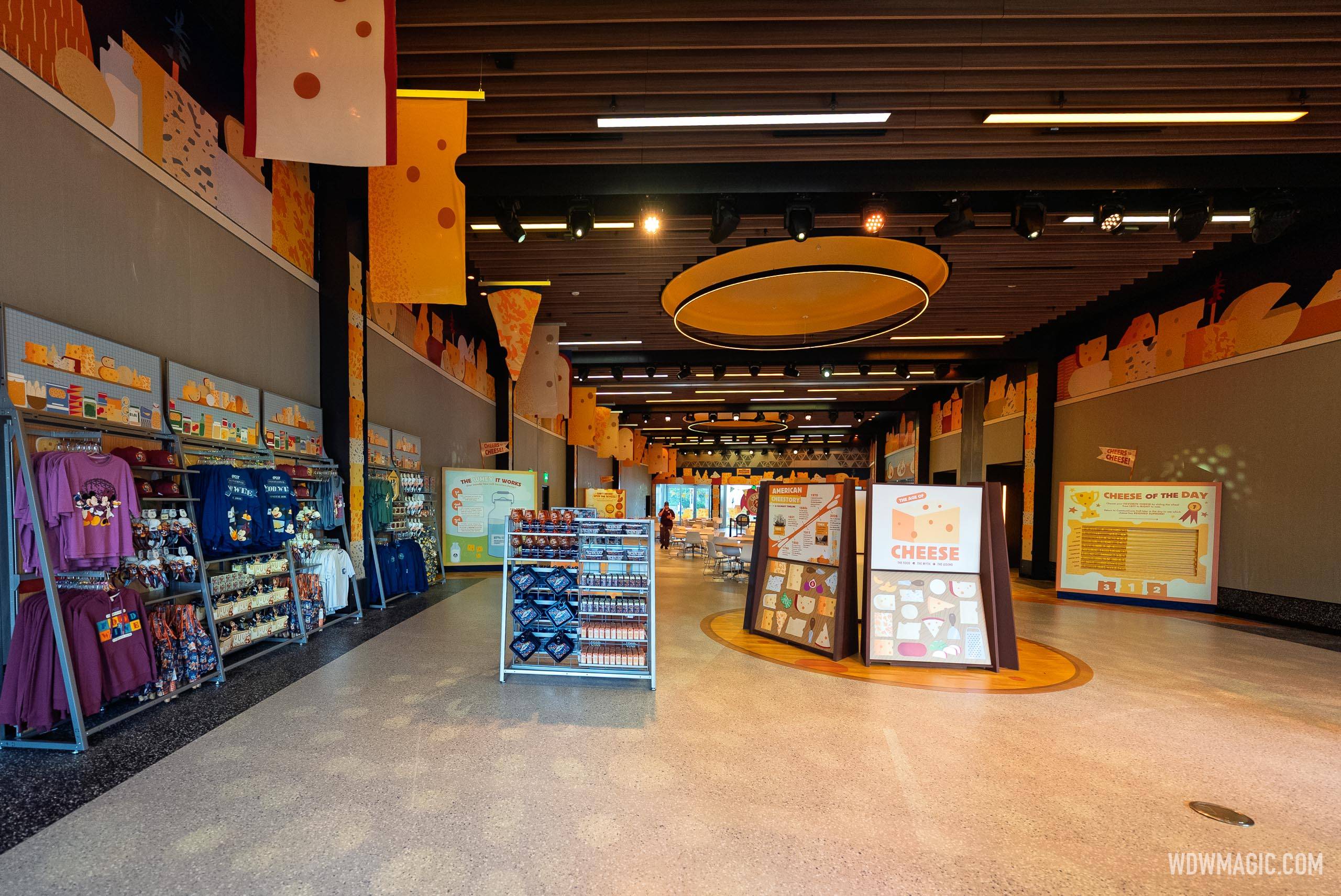 Inside CommuniCore Hall, merchandise racks, and "American Cheese" exhibit panels are visible beneath orange cheese-themed wall murals