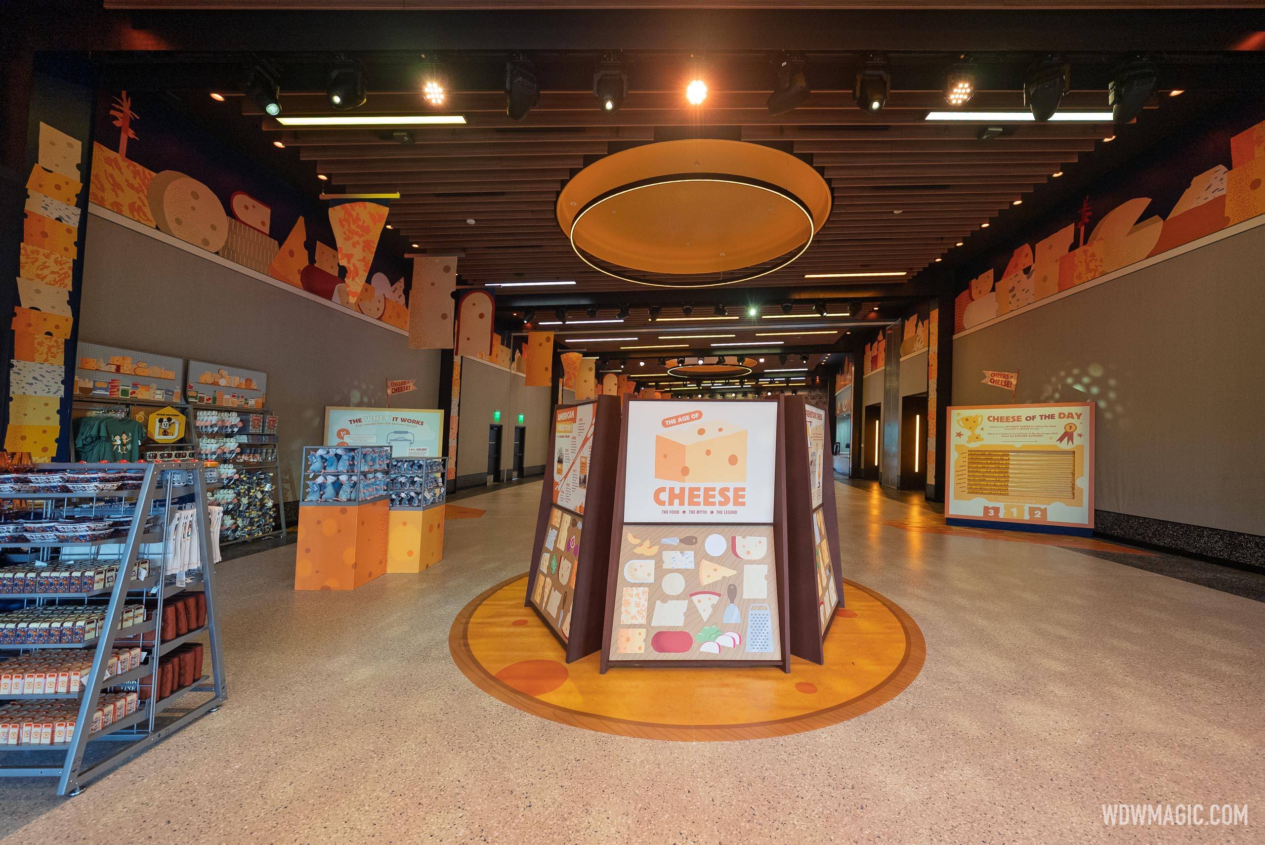 Inside CommuniCore Hall, a central "Big of Cheese" display panel and "Cheese of the Day" signage are surrounded by cheese-themed murals lining the walls