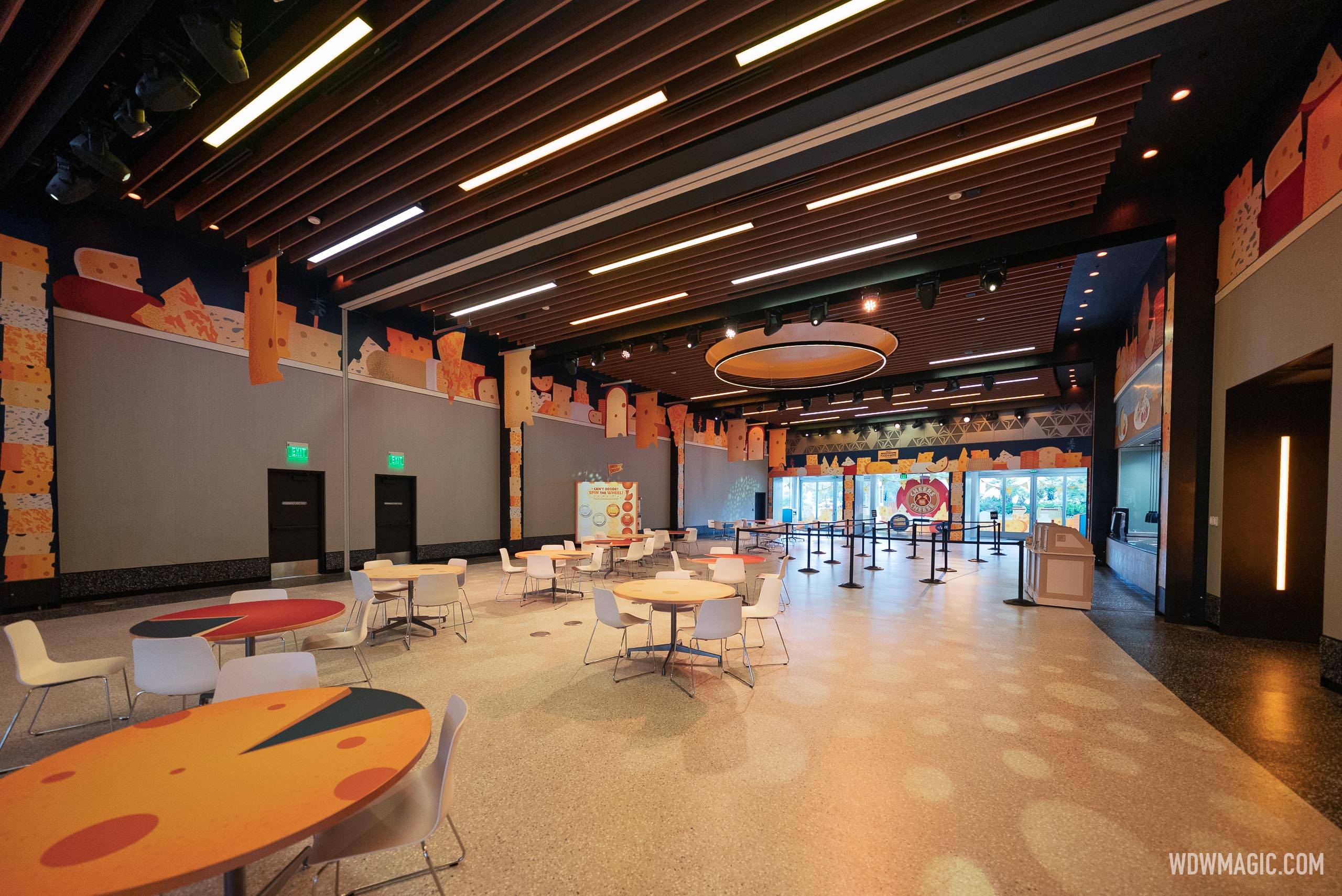 Interior of CommuniCore Hall showing cheese-themed wall murals, colorful food-themed tables