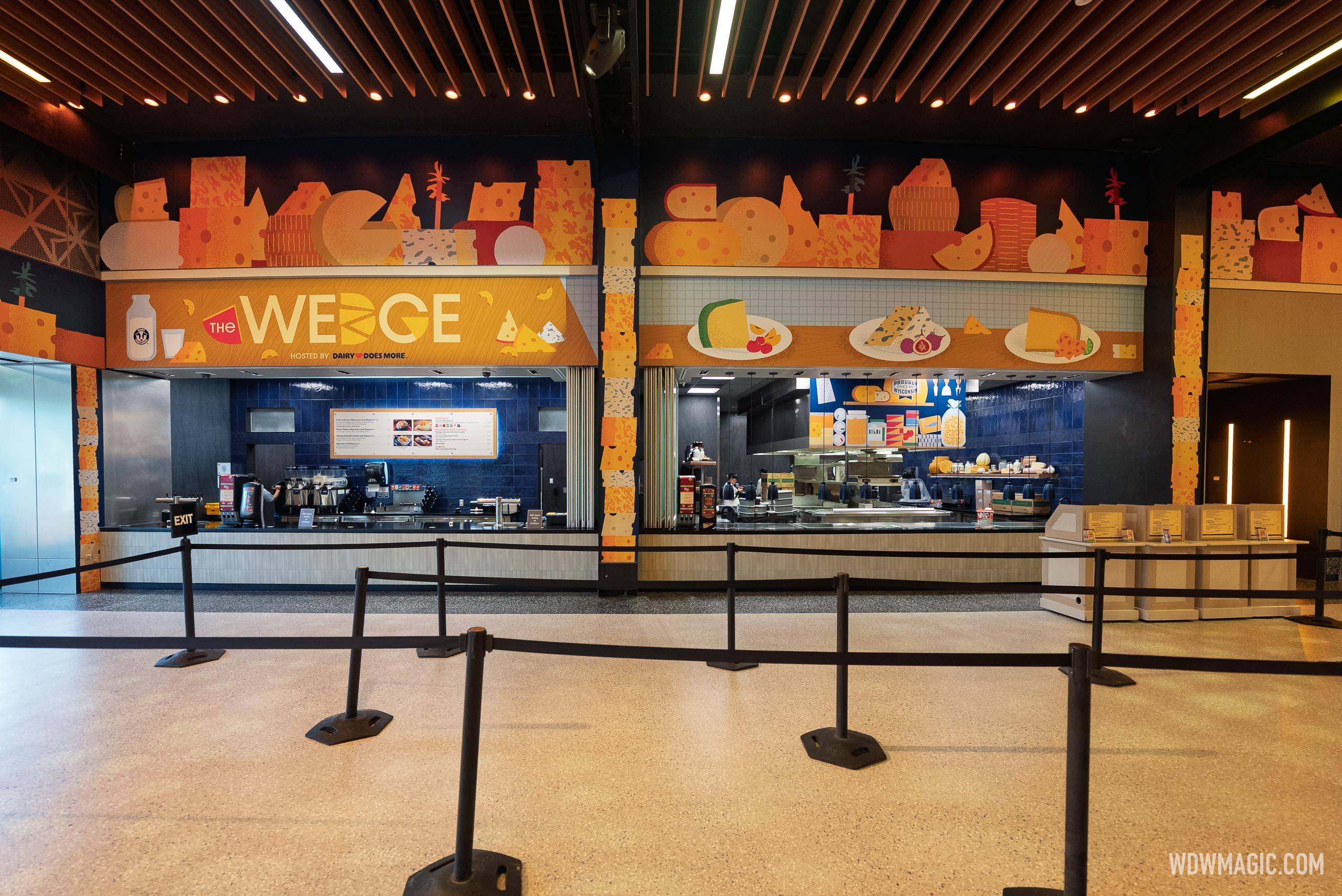 The Wedge marketplace booth, hosted by Dairy Does More, viewed from the queue area with cheese-themed wall murals above the service counter