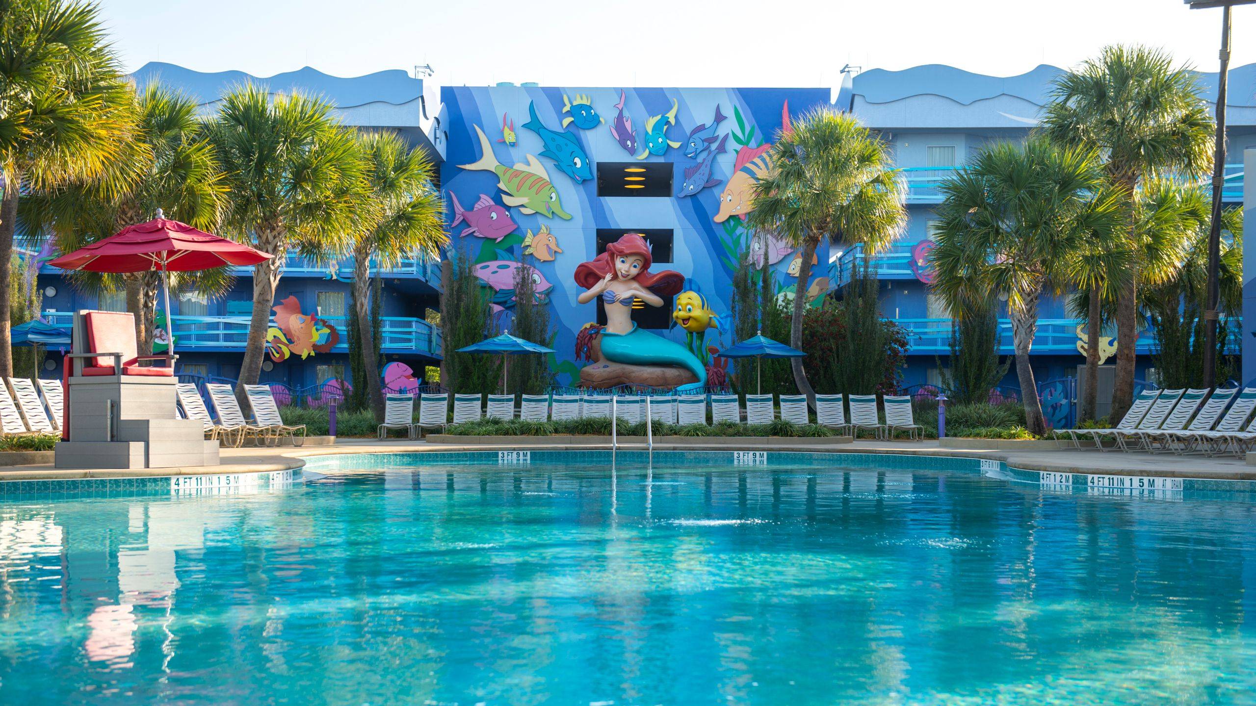 The Little Mermaid pool area at Disney's Art of Animation Resort, featuring a large Ariel statue and undersea-themed building murals