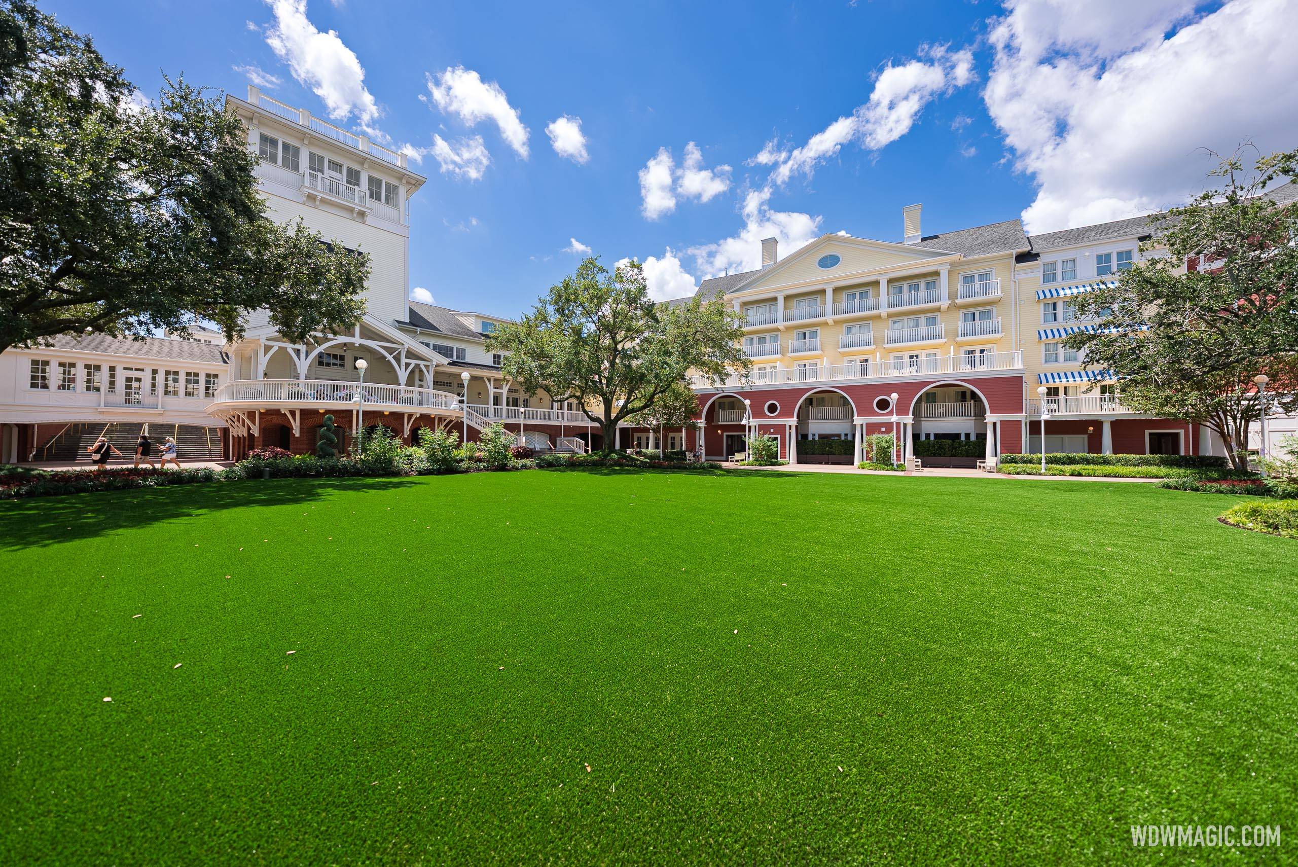 The newly installed artificial turf at Disney's BoardWalk Inn Village Green, with the resort's yellow building and brick rotunda visible in the background