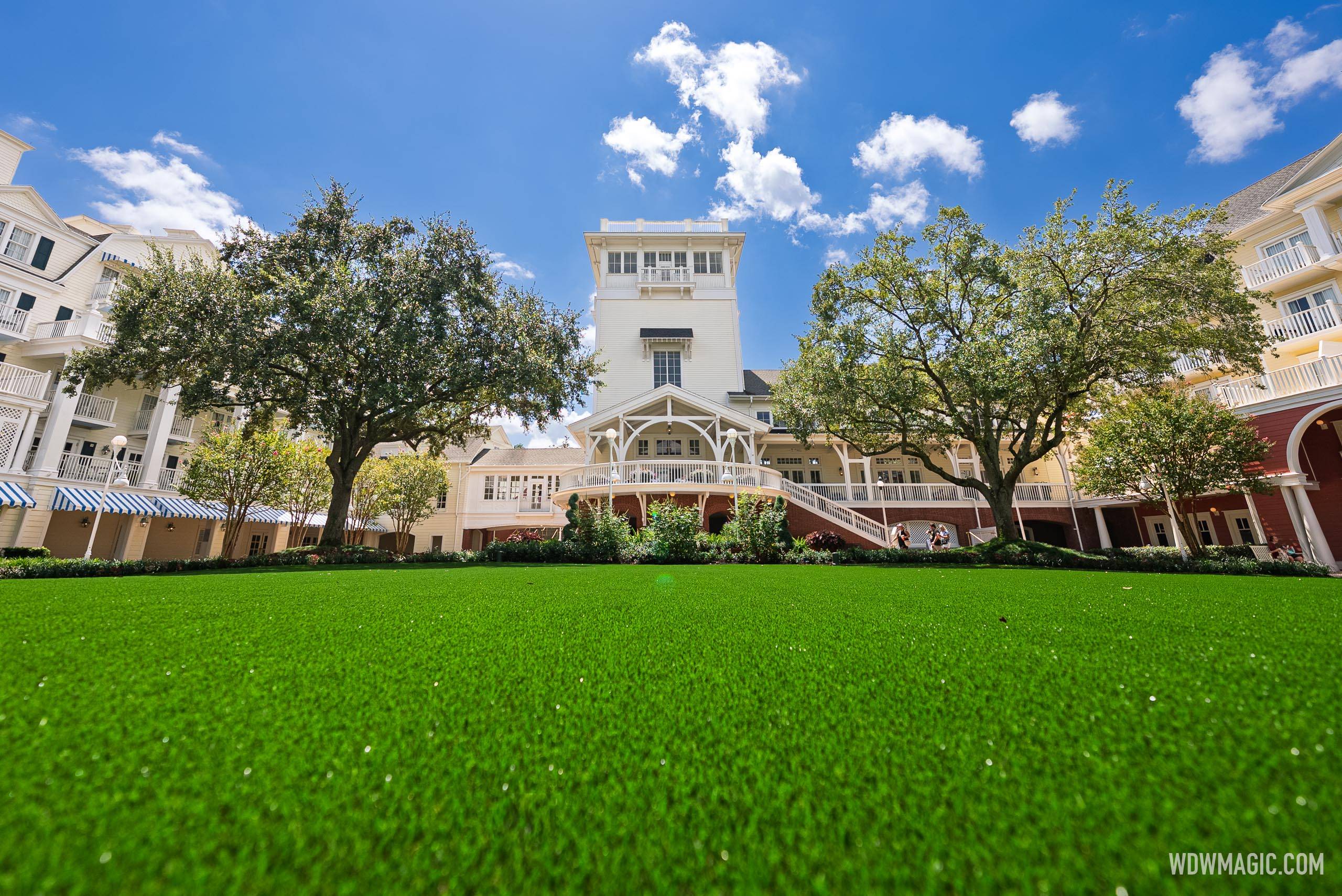 The Village Green courtyard at Disney's BoardWalk Inn, showing the newly installed artificial turf with the resort's main building and tower in the background
